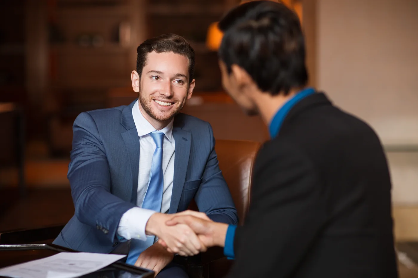 Two attorneys shaking hands with a new client in a law firm conference room