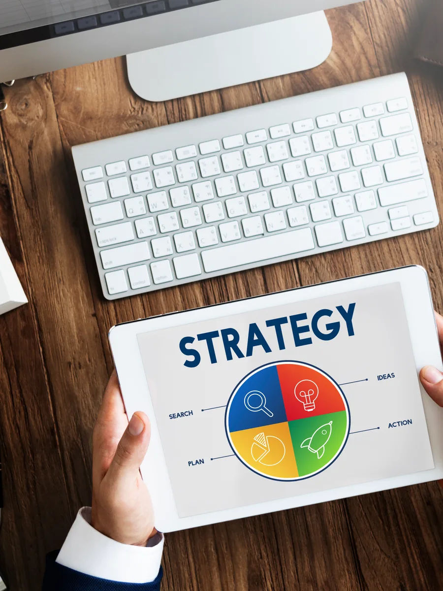 Startup marketing team reviewing PPC campaign performance data on a laptop and whiteboard